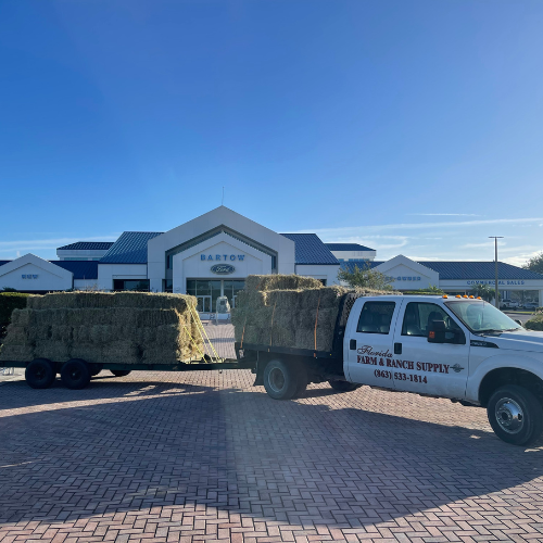 Florida Farm & Ranch branded truck parked in a lot pulling a trailer of hay.