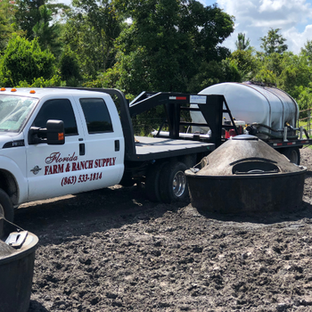 A Florida Farm & Ranch branded truck pulling a tank across a pasture.