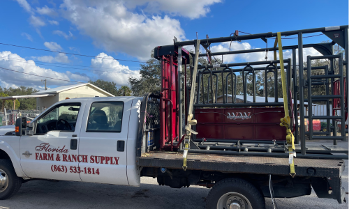 Florida Farm & Ranch branded truck parked in a lot pulling a trailer of gates.